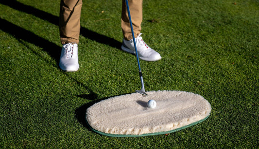 A golfer addressing a ball on the WhyGolf Bunker Mate, wedge resting on the fleece surface