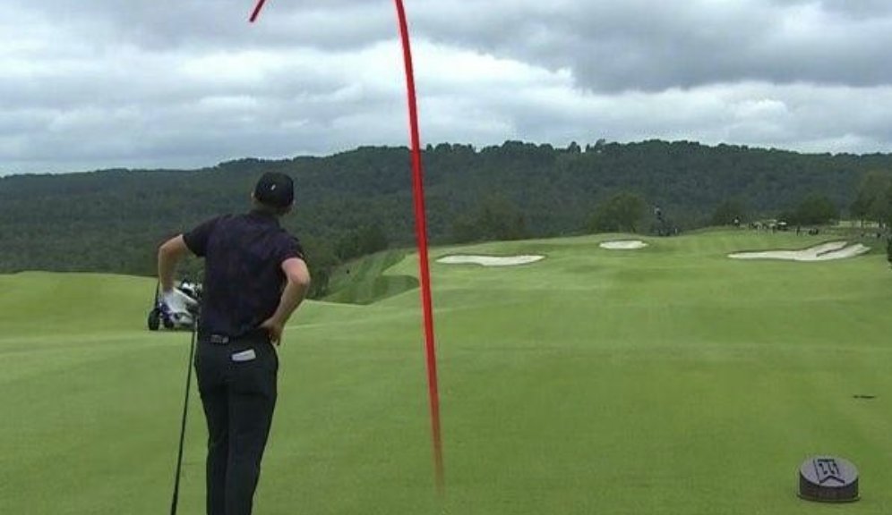 Golfer watching a curving ball flight from the tee