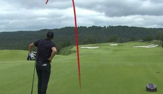 Golfer watching a curving ball flight from the tee