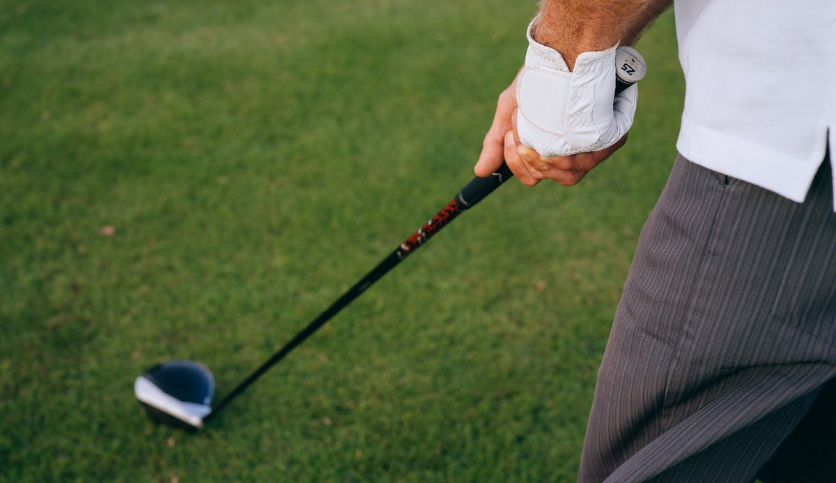 Close-up of a golfer gripping a driver on the tee, where every betting game starts