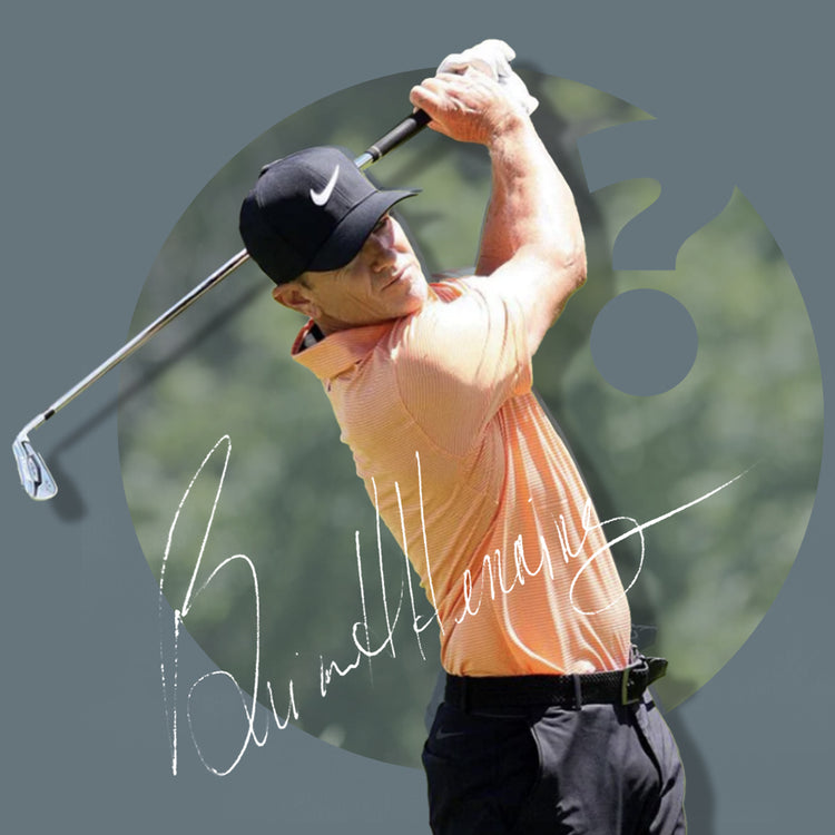 Golf player in mid-swing, wearing an orange shirt and black cap.