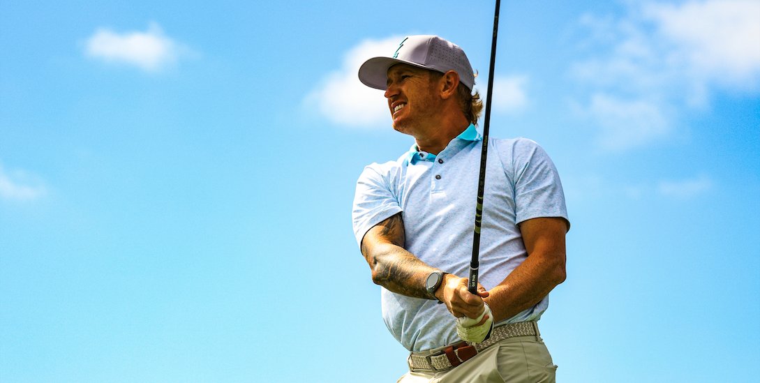 Nik Neal watching a tee shot against a blue sky