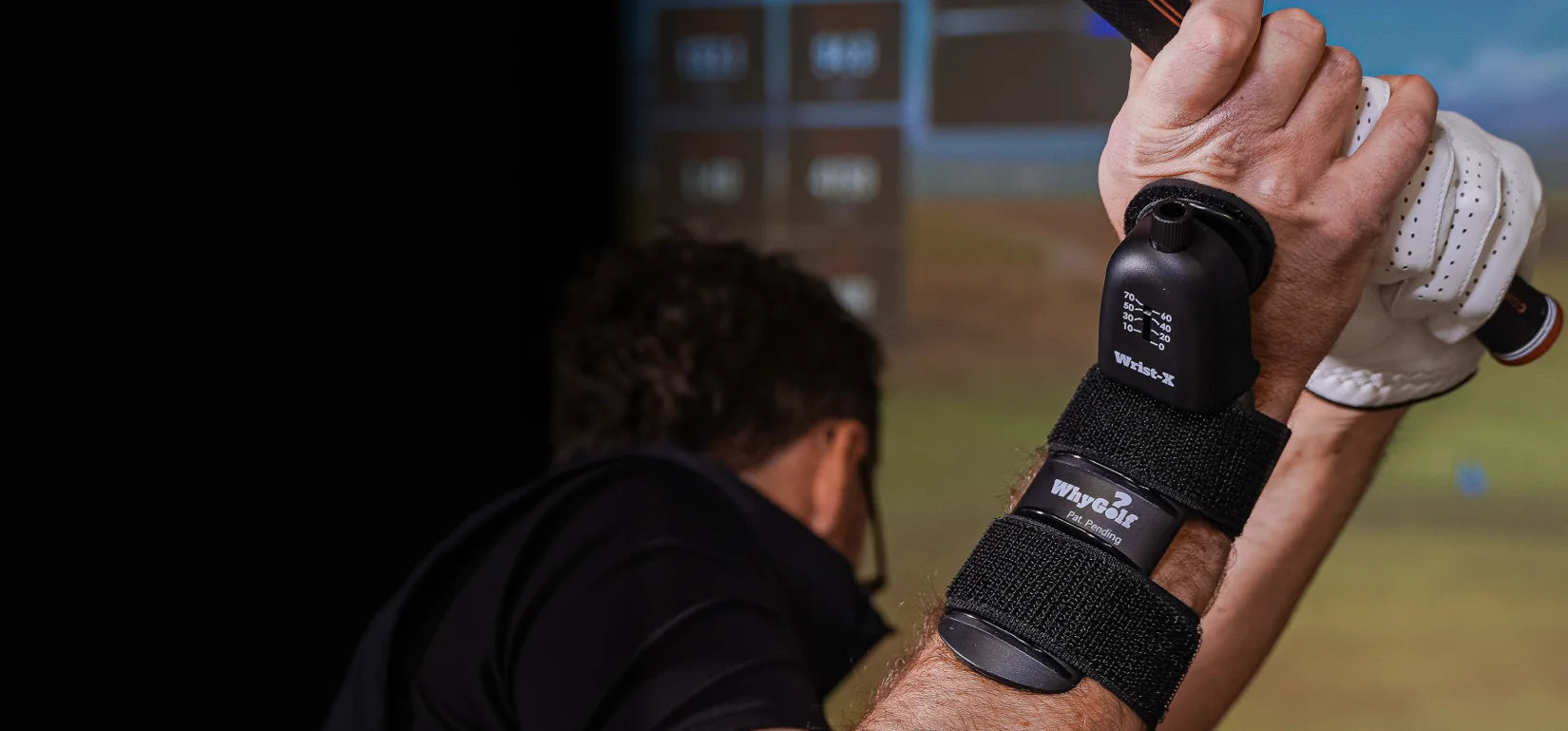 Golfer at the top of the backswing wearing the WhyGolf Wrist-X wrist trainer