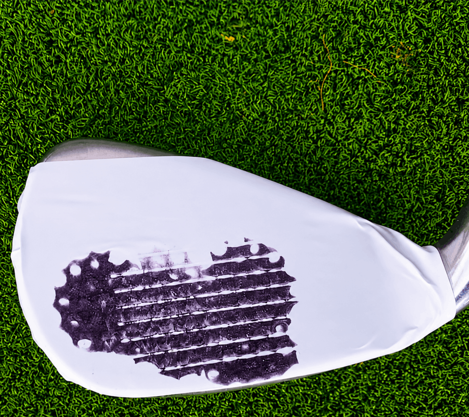 Clubface impact tape showing strikes scattered across the face